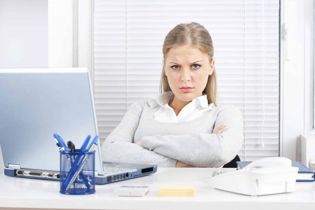 Unhappy woman seated with arms crossed and furrowed brow